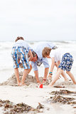 father and sons on the beach playing in the sand
