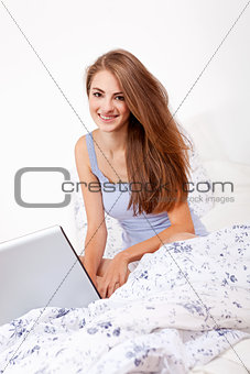 smiling woman sitting on bed with notebook