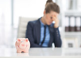 Closeup on piggy bank on table and stressed business woman in ba