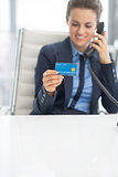 Closeup on business woman with credit card talking phone