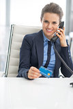 Happy business woman with credit card talking phone