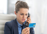 Closeup on business woman with credit card talking phone