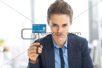 Serious business woman cutting credit card with scissors