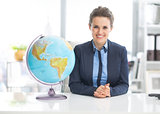 Portrait of happy business woman near earth globe