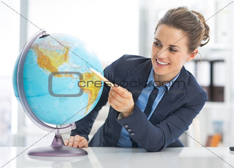 Portrait of happy business woman pointing on earth globe