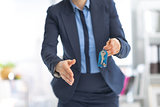 Closeup on happy business woman giving keys and stretching hand 