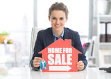 Realtor woman showing keys and home for sale sign