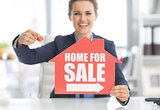 Closeup on happy realtor woman pointing on home for sale sign