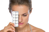 Portrait of serious young woman with blistering package of pills