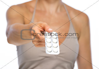 Closeup on young woman giving blistering package of pills