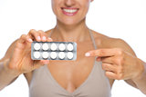 Closeup on young woman pointing on blistering package of pills