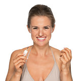 Portrait of smiling young woman applying nail polish