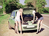 Two blonde girls standing by the broken car 