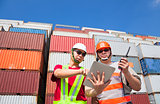 two workers with tablet  and standing before stack of containers