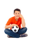 young man sitting and hold a soccer