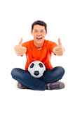 young man sitting with a soccer and thumb up