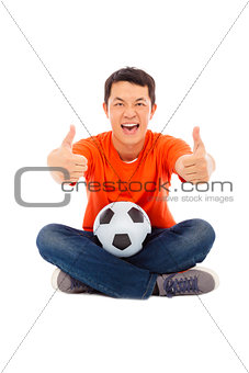 young man sitting with a soccer and thumb up