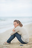 Calm young woman sitting on cold beach