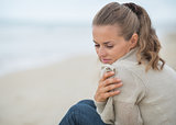 Portrait of calm young woman sitting on cold beach