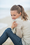 Calm young woman sitting on cold beach