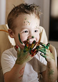 Excited little boy playing with finger paints