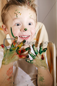 Cute excited boy with hands full of finger paint