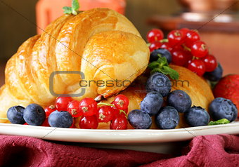 fresh croissant with berries for breakfast on vintage plate