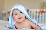 Smiling baby in a hooded towel after bath