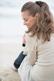 Happy woman sitting on cold beach. rear view