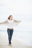 Full length portrait of young woman walking on cold beach and re