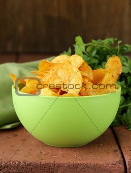 natural potato chips with paprika in a bowl on a wooden table
