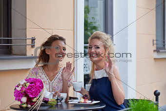 two beautiful young girls in summer outfit have lunch at the tab
