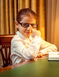 Young girl in eyeglasses sitting behind desk