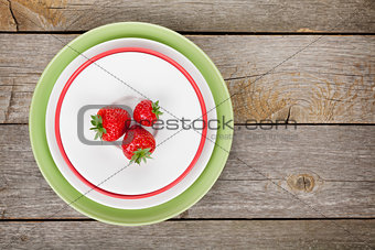 Ripe strawberries on plate over wooden table background