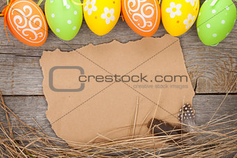Easter eggs and paper for your greetings on wooden background