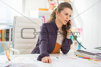 Concerned fashion designer talking phone in office