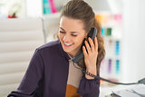 Happy fashion designer talking phone in office