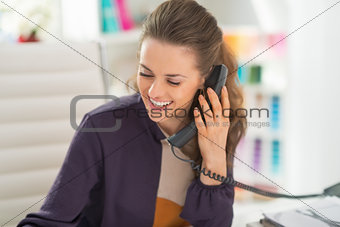 Happy fashion designer talking phone in office