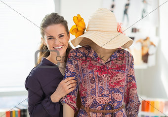 Portrait of happy fashion designer near mannequin