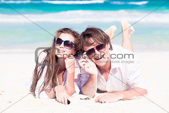 Portrait of happy young couple in bright clothes and sunglasses having fun on tropical beach