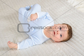 Cute baby boy is lying on the gray carpet