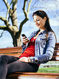 Beautiful woman using smartphone on park bench
