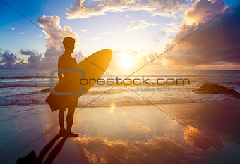 surfer man standing on beach and holding a surfboard