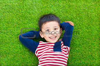 happy kid lying and holding his head on a meadow