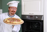 Young chef smelling italian pizza in kitchen