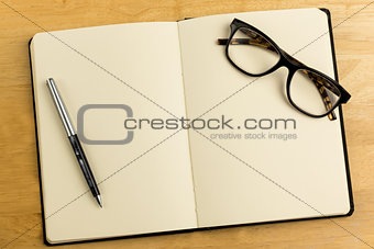 Overhead of open notebook with pen and glasses