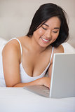 Pretty asian lying on bed using laptop