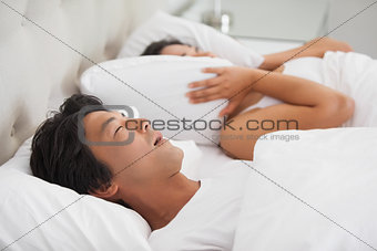 Woman covering her ears as partner is snoring loudly