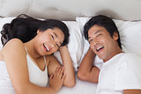Happy couple lying in bed smiling at camera