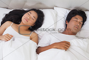 Happy couple lying in bed asleep